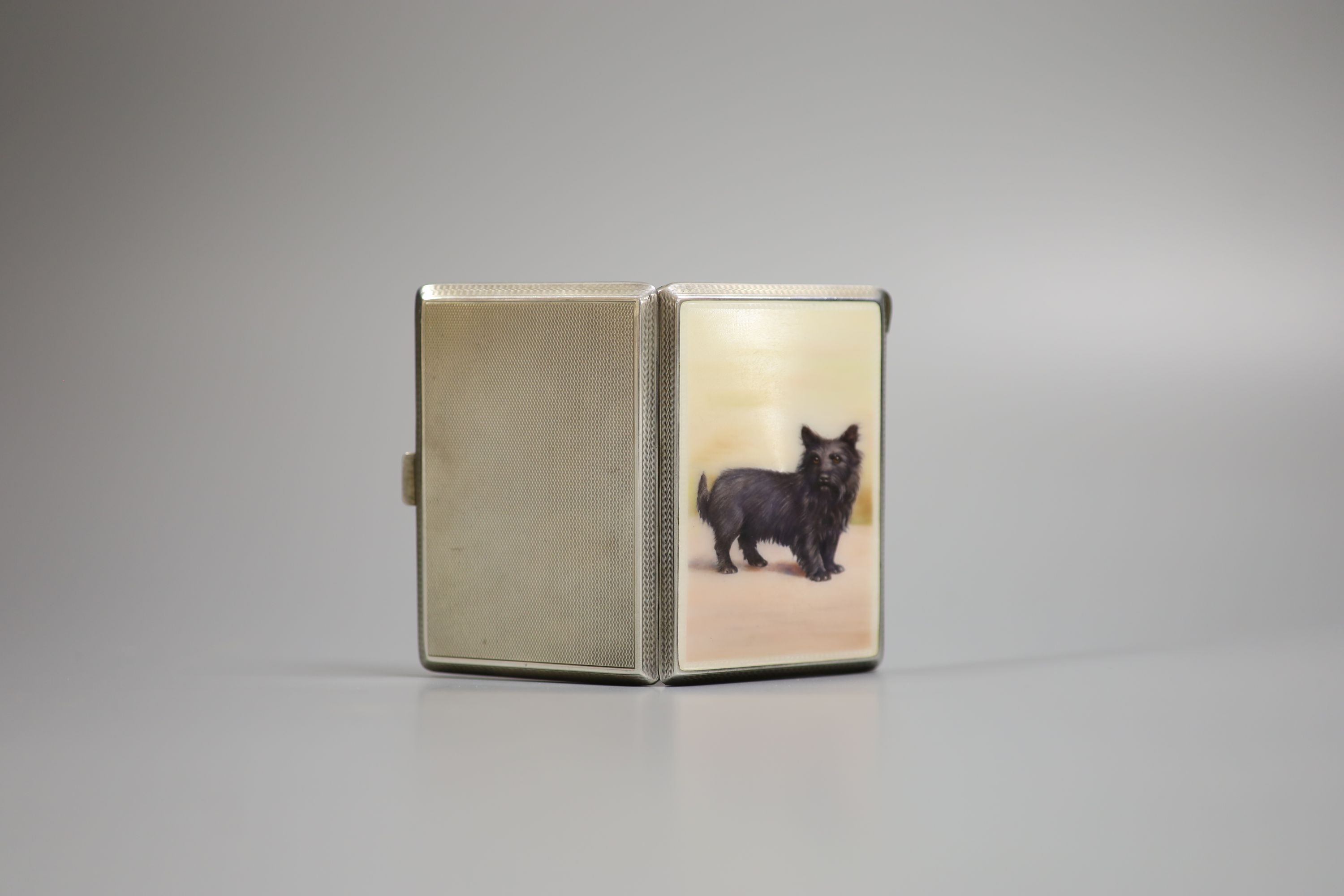 A George V silver and enamel cigarette case, the enamel decorated with a dog, import marks for London, 1928, 87mm.